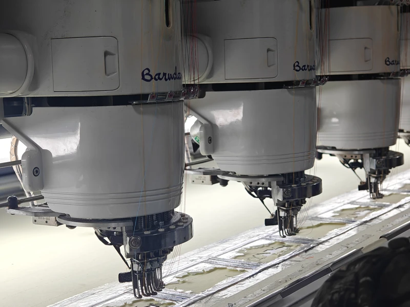 Close-up of embroidery machine heads and needles in the BDBRIM workshop
