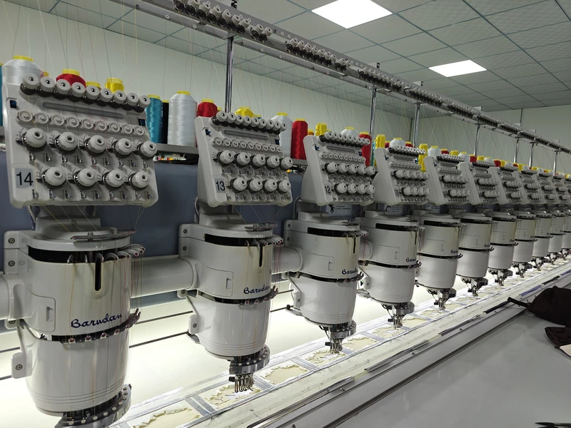 A row of multihead embroidery machines and thread spools in the BDBRIM workshop