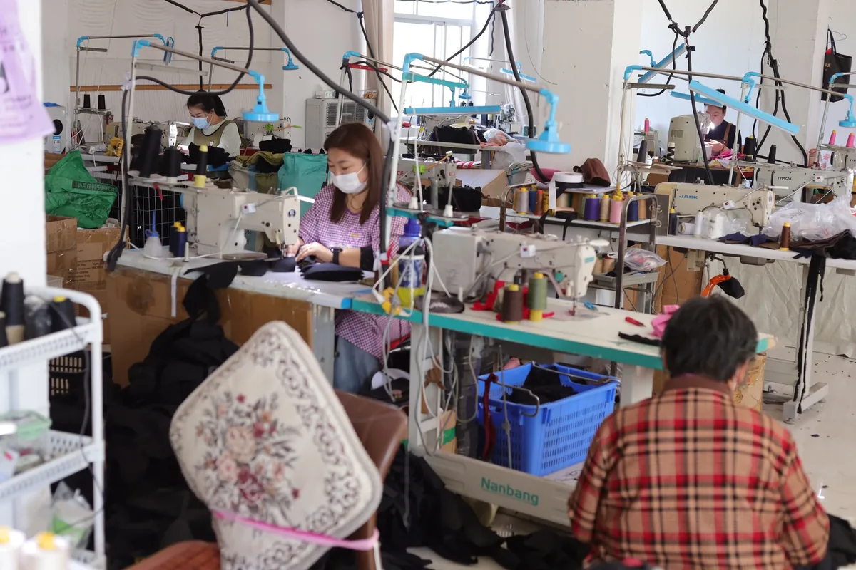 Operators at industrial sewing stations with cap components in the BDBRIM workshop