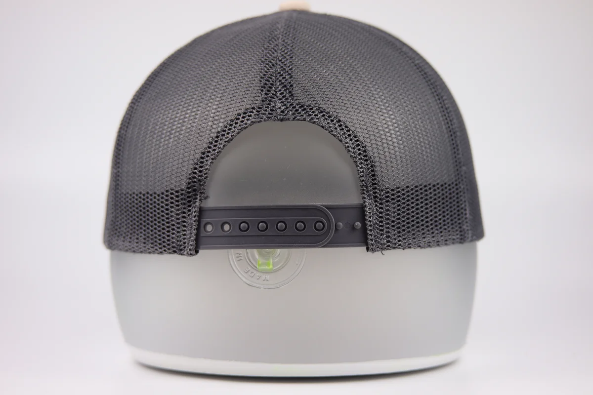 Rear of the cream and grey round-patch trucker cap showing grey mesh and black plastic snapback