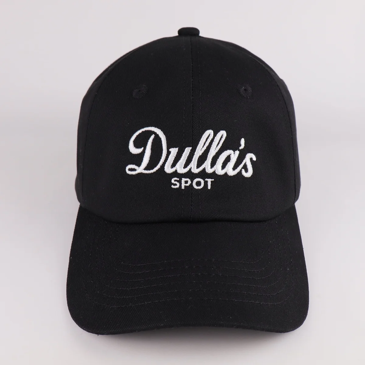 Front view of a black baseball cap with white script embroidery