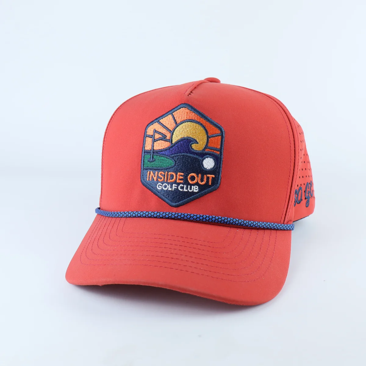 Coral red golf cap with multicolor crest patch and blue visor rope