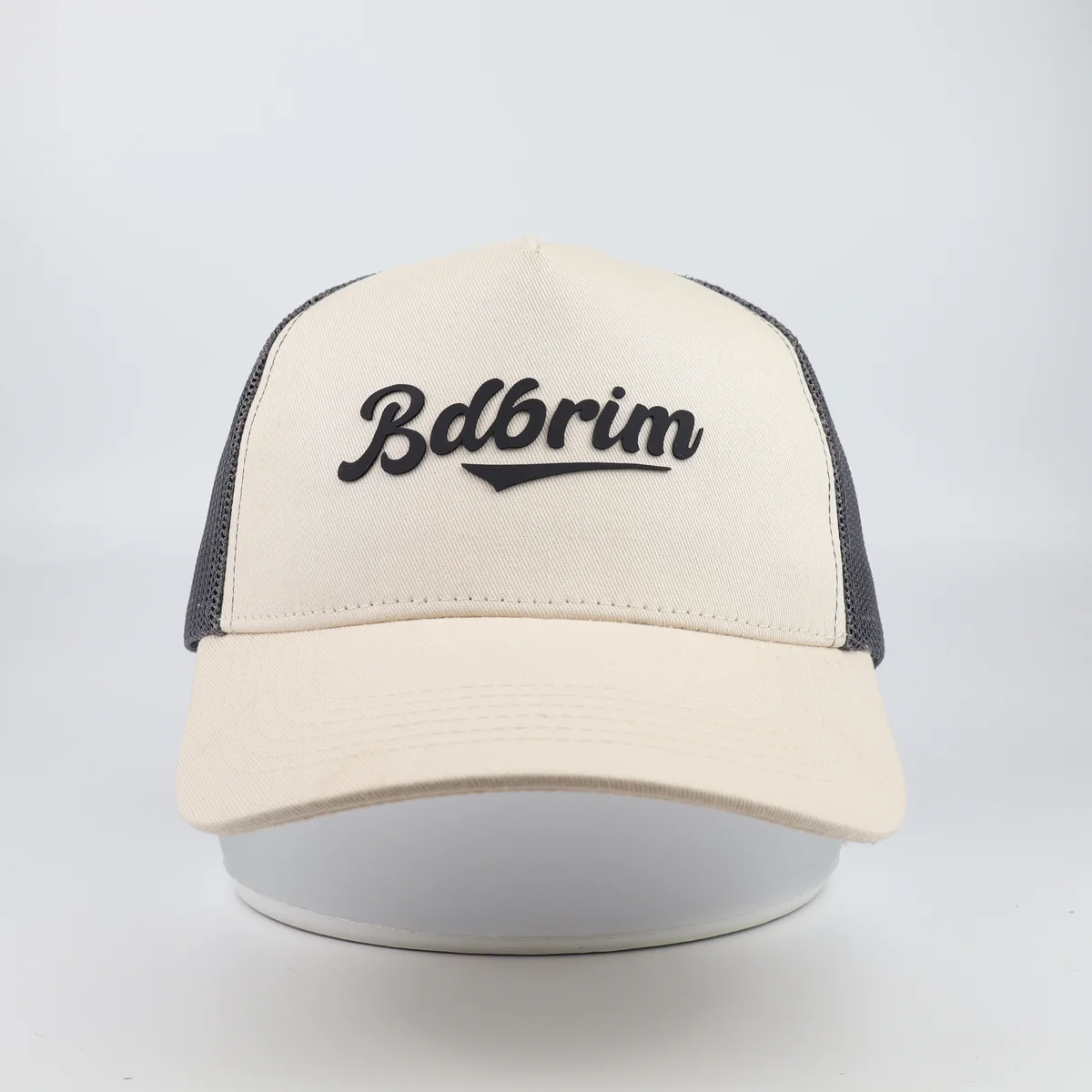 Cream trucker cap front panel showing black lettering and mesh sides