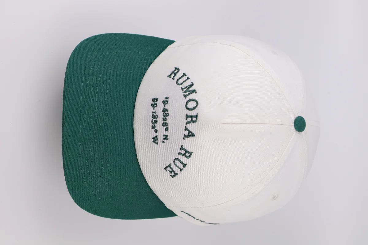 Top view of cream crown with green bill and arched lettering