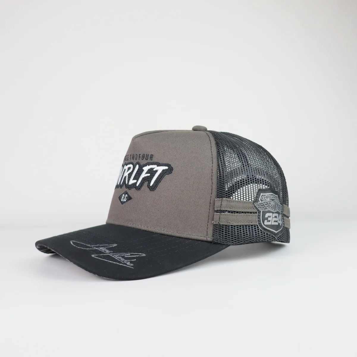 Angled profile of gray front black mesh trucker cap with decorative patches