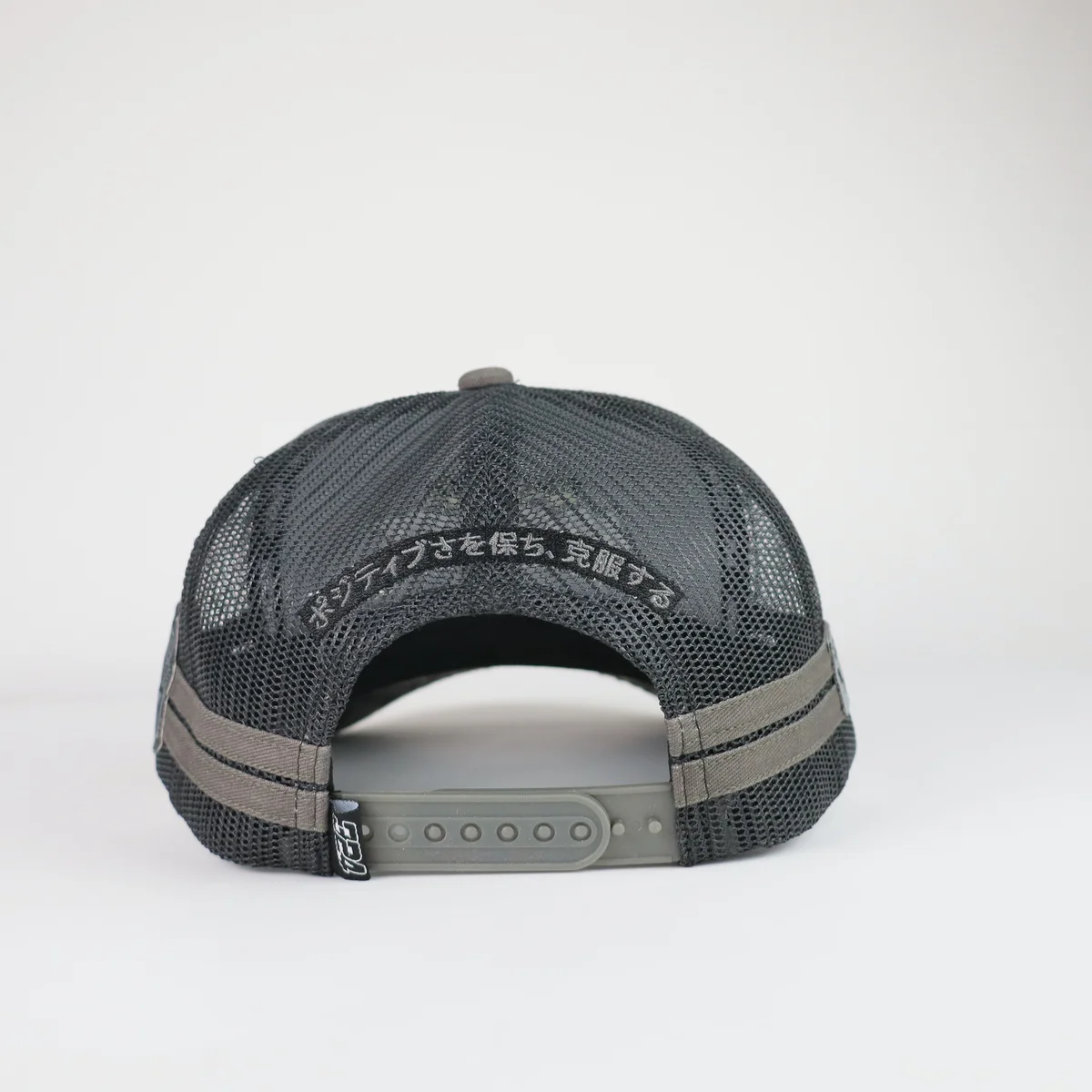Rear view of black mesh trucker cap showing snap closure and embroidered opening