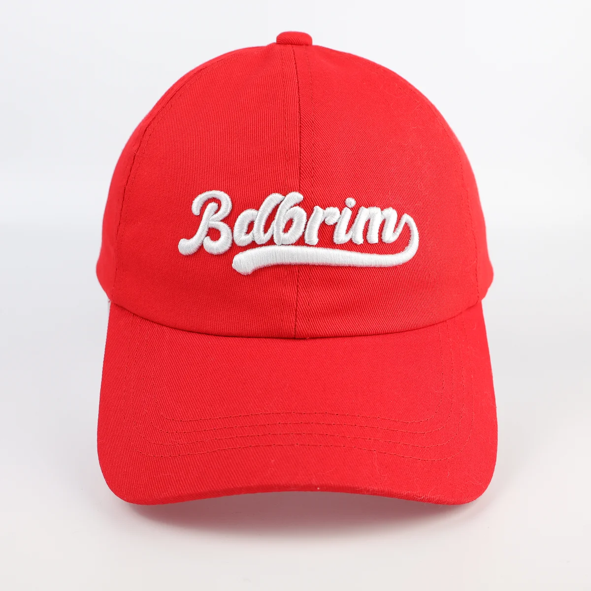 Front view of a red curved-brim baseball cap with white script embroidery