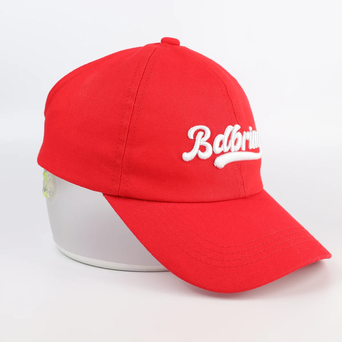 Angled side view of the same red baseball cap with white front embroidery