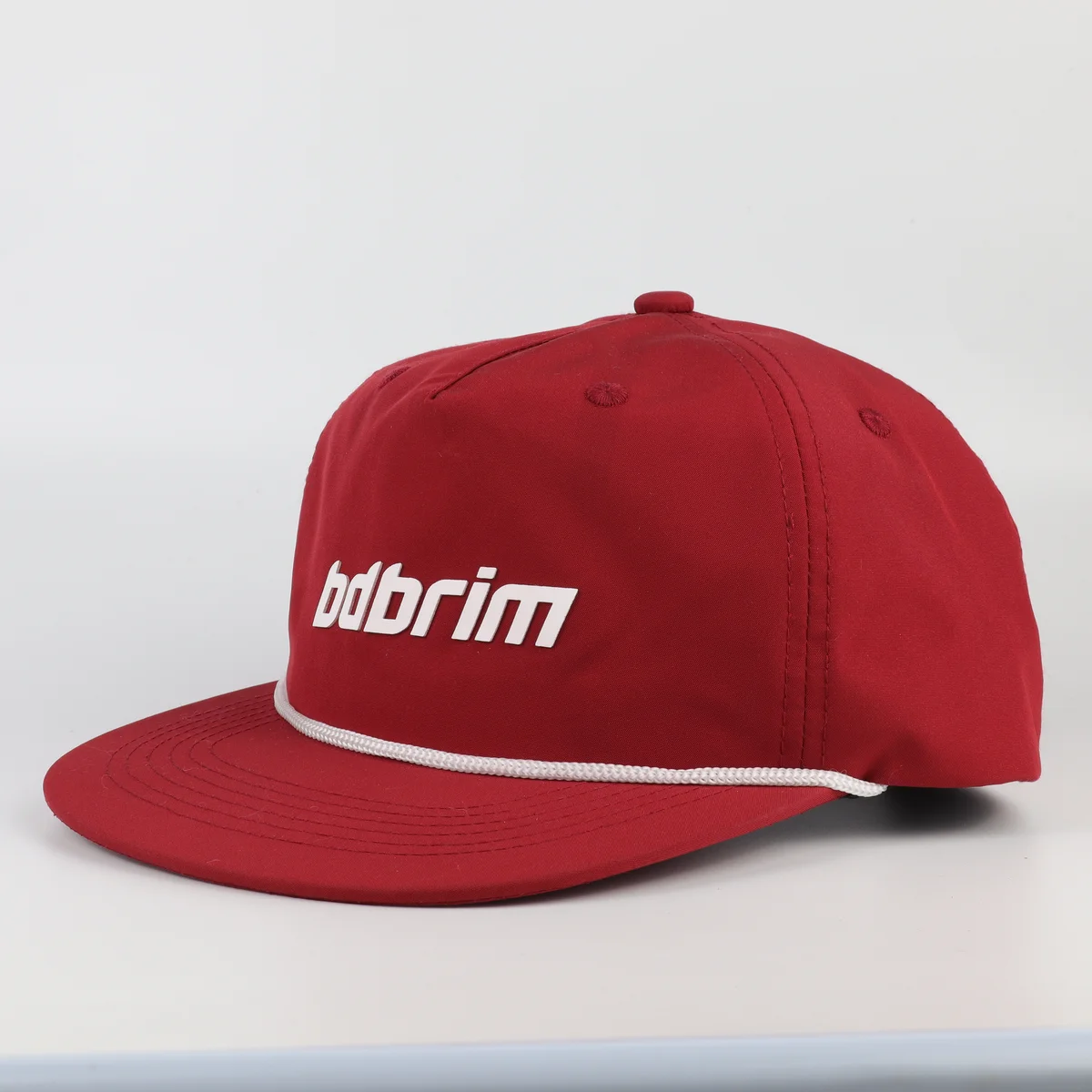 Red rope trim golf cap with white cord across visor and white front lettering
