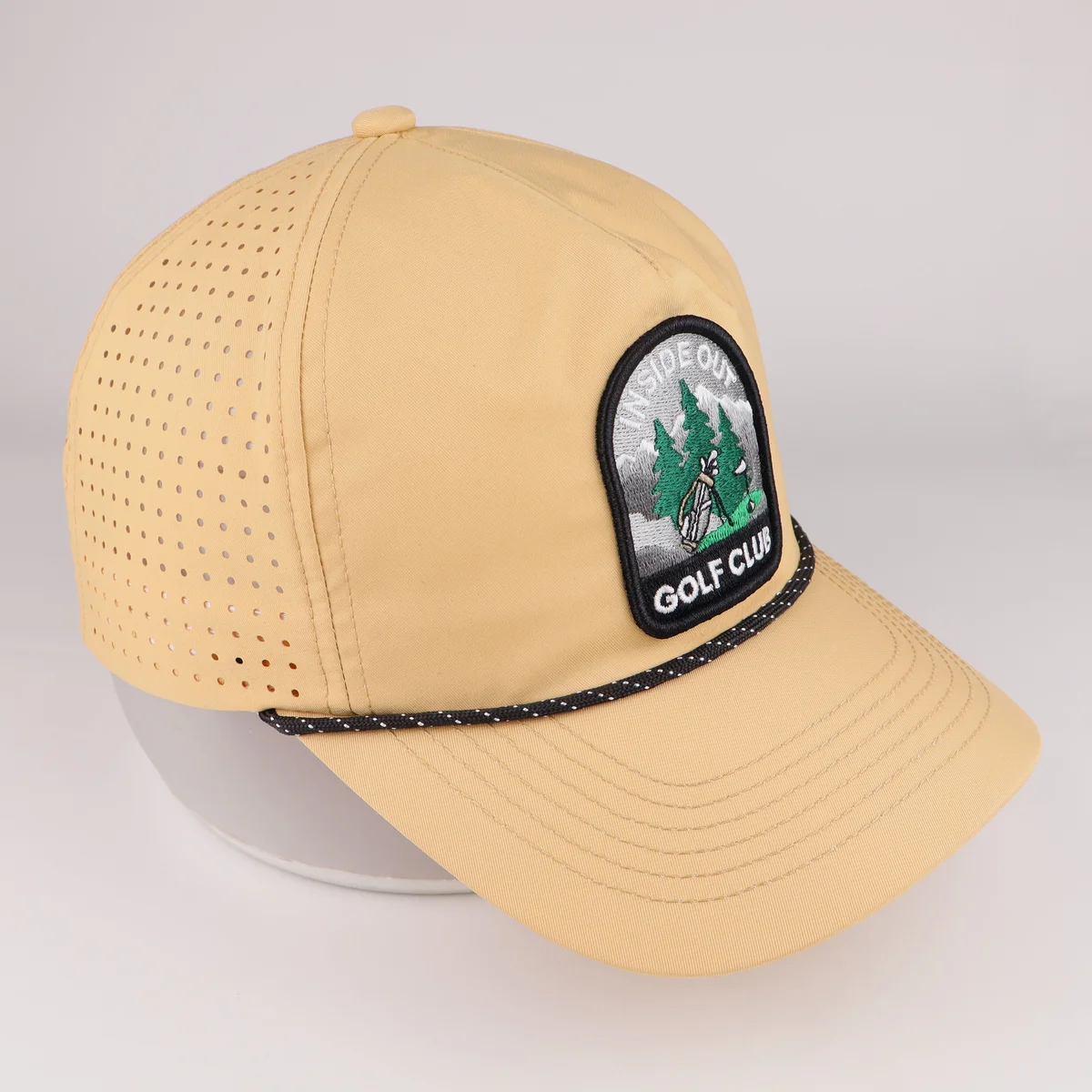 Additional side view of tan golf cap with embroidered club badge