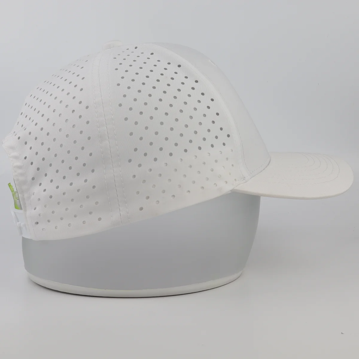 Side view showing multiple perforation holes across a white performance cap