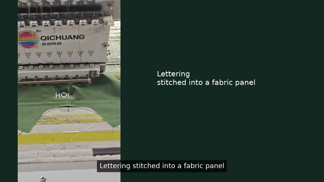 Lettering being embroidered on a green fabric panel in the BDBRIM workshop
